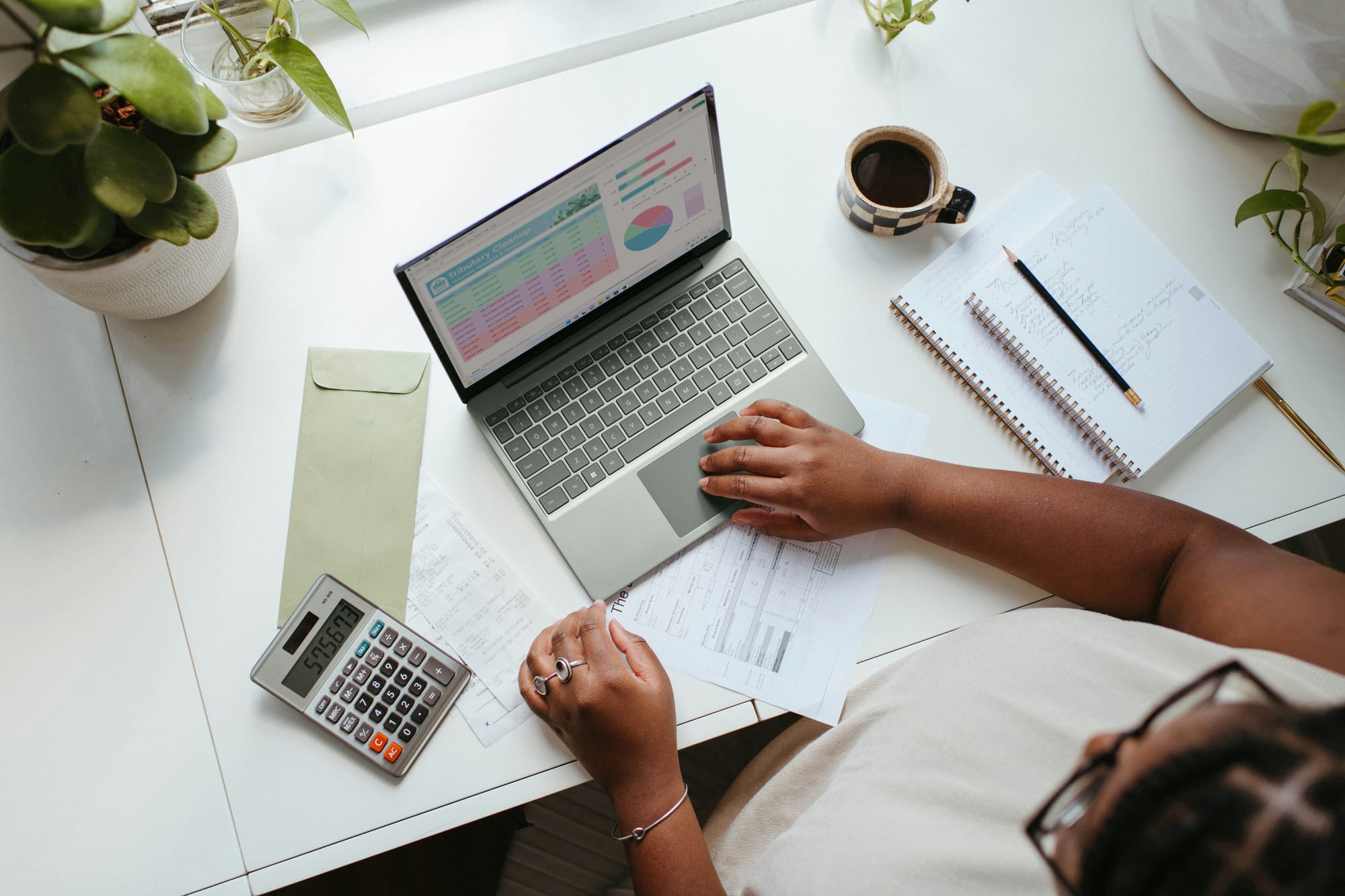 female sitting at desk with laptop, calculator and documents